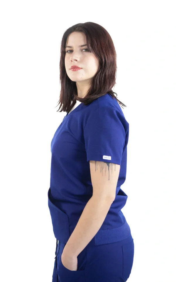 A woman in blue scrubs is standing up.